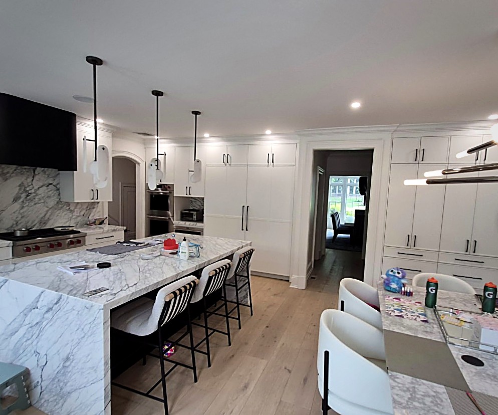 Finished GSR kitchen with a book-matched marble waterfall island, white cabinetry and wide-plank floors