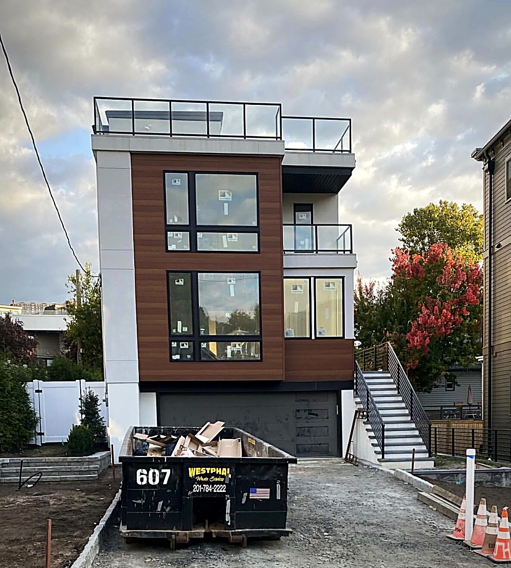 A completed modern GSR home at dusk with a rooftop deck, wood clad façade and black framed glass