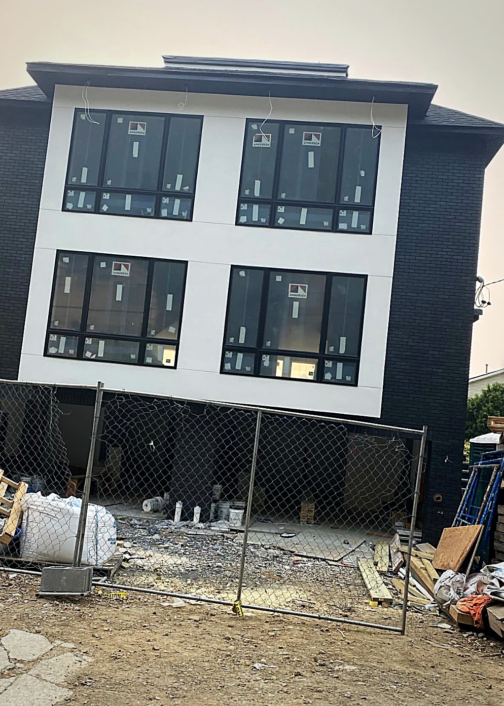 A GSR modern home nearing completion, white stucco and black brick with large black framed windows